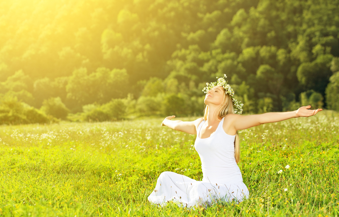 lady sat in field with flowers in hair and hands open